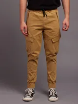 Pantalón cargo color ocre de sarga, con cintura elástica ajustable con cordón, bolsillos laterales con cierre y bolsillos cargo con solapa en los muslos.