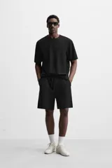 Bermuda negra de corte relaxed fit, con cintura elástica ajustable con cordón, bolsillos frontales y bolsillo trasero de parche.