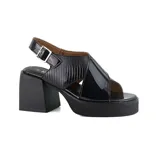 Sandalias negras de cuero charol con plataforma y taco ancho. Presentan tiras cruzadas en el empeine, una tira trasera con hebilla y una sección con textura de piel de reptil.