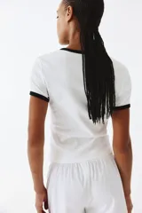 Remera blanca entallada de punto suave con ribete fino negro en cuello y mangas cortas.