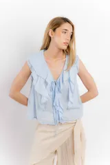 Blusa blanca de algodón con escote en V, volados en el frente y mangas cortas.