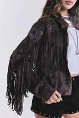 Campera marrón de gamuza sintética con flecos en el pecho y mangas, bordado de flores en el frente y cierre frontal con cremallera.