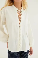 Camisa blanca de popelina de algodón con mangas largas abullonadas y cordones cruzados en los laterales.