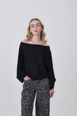 Sweater negro de manga larga, con escote asimétrico que deja un hombro al descubierto. Diseño holgado.