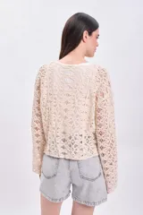 Sweater de crochet color crudo con mangas largas acampanadas.