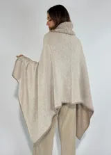 Ruana color beige confeccionada en 100% lambswool, con cuello alto y detalles bordados a mano en el borde.