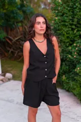 Conjunto de dos piezas color rojo vibrante, compuesto por un chaleco sin mangas con escote en V y botones frontales, y un short de tiro alto con pliegues y bolsillos laterales.