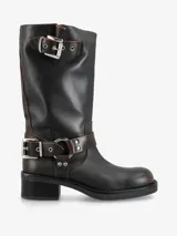 Bota de caña media de cuero negro, estilo biker, con caña arrugada y detalles de correas con hebillas metálicas plateadas en la parte superior y alrededor del tobillo. Posee un taco bajo y grueso.