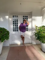 Camisa de seda con estampado de rayas verticales azules, rojas y blancas, con cuello clásico, manga corta con dobladillo y cierre frontal con botones blancos.