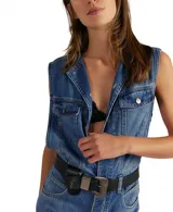 Overol de denim azul, sin mangas, con cuello camisero y cierre frontal. El pantalón es de corte chupín ajustado al cuerpo.