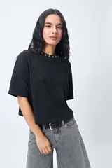 Remera negra de corte holgado con mangas ranglan y cuello redondo con bordado de estrellas blancas.