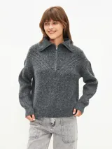 Sweater gris de tejido de punto grueso, con cuello polo con cierre de cremallera metálica y mangas largas.