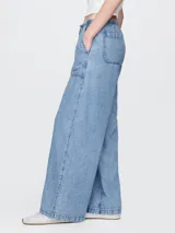 Pantalón de jean celeste claro, corte amplio, con cintura elástica ajustable con cordón, bolsillos laterales y traseros.