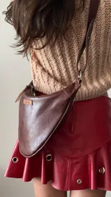 Riñonera de cuero marrón con correa ajustable para usar como bandolera o cinturón. Diseño minimalista con logo de la marca en el frente. Hecha a mano con cuero 100% natural.