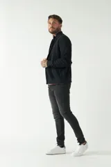 Campera negra de felpa con cierre frontal, bolsillos laterales, puños y logo bordado en el pecho.