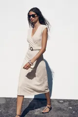 Vestido midi color crudo con jacquard floral, escote pico cruzado, manga sisa caída y cinturón ajustable con hebilla.