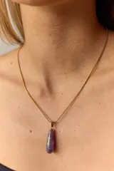 Collar dorado con cadena fina y dije colgante en forma de lágrima de piedra natural azul con vetas blancas.