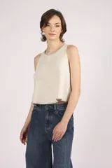 Blusa sin mangas color crema, con cuello redondo y bordes con pespuntes en contraste.
