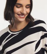 Blusa de viscosa color crudo con estampado abstracto en negro. Tiene cuello redondo y mangas cortas con recorte.