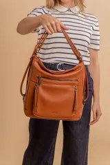 Cartera mochila color marrón de símil cuero suave con múltiples bolsillos con cierre, división al medio y correa ajustable de doble manija para llevar al hombro y como mochila.