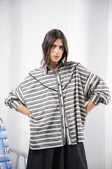 Camisa oversize a rayas horizontales en tonos gris y blanco, con cuello clásico, cierre frontal con botones, mangas largas con puños abotonados, recorte delantero con vivo contrastante negro y logo bordado al frente.