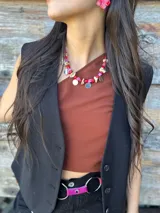 Collar corto con cuentas irregulares de piedra en tonos rosados y beige, cuentas de nácar y dijes circulares metálicos en tonos plata y oro.