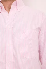 Camisa celeste con rayas verticales blancas, de corte clásico, con cuello abotonado, manga larga y bolsillo en el pecho.