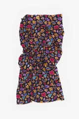 Pareo de algodón con estampado vibrante sobre fondo negro. El diseño presenta figuras abstractas y estilizadas en tonos de azul, rojo, amarillo y morado, con un borde deshilachado.