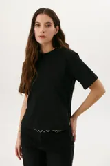 Remera blanca de algodón de corte recto, con cuello redondo y mangas cortas. Presenta detalle de aberturas laterales con ojales metálicos.