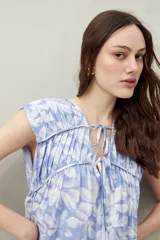 Vestido largo con estampado floral celeste y blanco, escote ajustable con lazo y frunce en la parte superior.