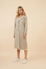 Tapado largo color beige con cuello solapa y corte recto. Cierre frontal con botones, detalles aplicados en la parte delantera, tajo en la espalda y bolsillos ojal con tapa. Con forro. Hecho en Uruguay con tela 100% lana fina sin teñir.