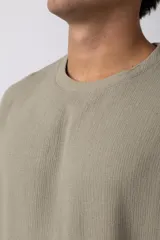 Remera color crudo de lino con textura entramada, calce cómodo y mangas cortas.