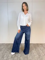 Camisa blanca de algodón con cuello clásico, corte recto y mangas largas con puños abotonados. Cierre frontal con botones.