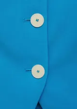 Chaleco azul con tirantes finos, escote cuadrado, cierre frontal con botones y espalda descubierta.