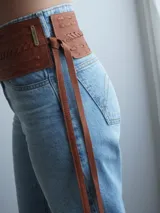 Faja ancha de cuero color marrón con detalles trenzados y lazo lateral con flecos en el extremo.