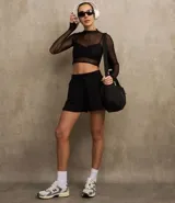 Blusa deportiva de tule negro, con cuello alto, mangas largas y estampa frontal con la palabra 'muse'.