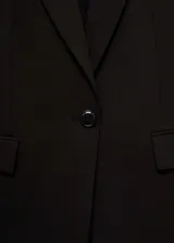 Blazer negro entallado con cuello de pico y solapa, hombros estructurados, abertura posterior, forro interior y dos bolsillos de ribete en la parte delantera.