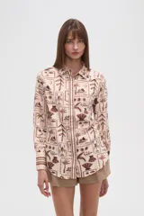 Camisa de manga larga con estampado de motivos playeros en tonos marrones sobre fondo beige, cuello camisero y cierre frontal con botones.