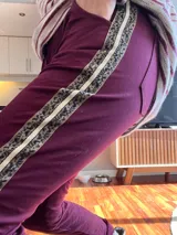 Pantalón bordó de corte recto, con bolsillos laterales y una franja dorada con estampado animal print en los laterales.