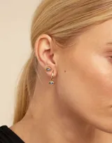 Pendiente tipo piercing en forma de ojo, de aleación de metales bañada en plata con cristal de Swarovski color light sapphire.