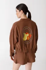 Bomber color coral confeccionada en mezcla de algodón y lino, con cierre frontal y puños elásticos. Presenta un bordado grande en la espalda inspirado en la colección La Verdulería.