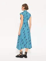 Vestido midi celeste con estampado de plumas negras, cuello alto y mangas cortas.