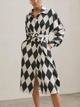 Vestido camisero midi con estampado geométrico de rombos en blanco y negro, cuello camisero, mangas largas y cinturón de lazo.