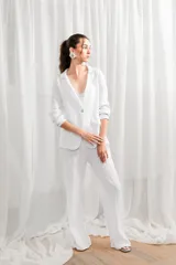 Blazer de lino blanco con estampado floral en tonos rosa y verde, corte holgado, cuello solapa y bolsillos laterales.