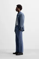 Pantalón azul de corte recto, con cintura ajustable, bolsillos laterales y traseros, y bolsillo tipo plastrón en la pierna. Tiene un lavado vintage con efecto de manchas.