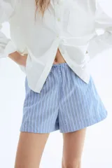 Short celeste con rayas verticales blancas y azules, cintura elástica con cordón ajustable y bolsillos laterales.
