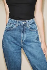 Jeans de tiro alto color negro con efecto lavado, corte mom fit, cinco bolsillos y cierre frontal con cremallera y botón metálico.