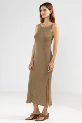 Vestido largo color dorado, tejido en punto jersey con hilo lurex, sin mangas, con escote bote redondeado y aberturas laterales.