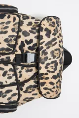 Mochila pequeña con estampado animal print, detalles en negro y múltiples bolsillos externos con cierre.