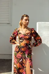 Vestido corto con estampado floral en tonos violeta, azul y amarillo. Tiene escote fruncido con cordones, mangas largas abullonadas y tajo lateral.